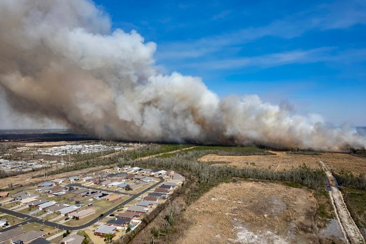 A fast-moving wildfire looms over homes outside of Panama City, Florida, on Friday. More than 200 firefighters and emergency workers from throughout the Florida Panhandle worked overnight into Saturday, to strengthen containment lines and protect homes.