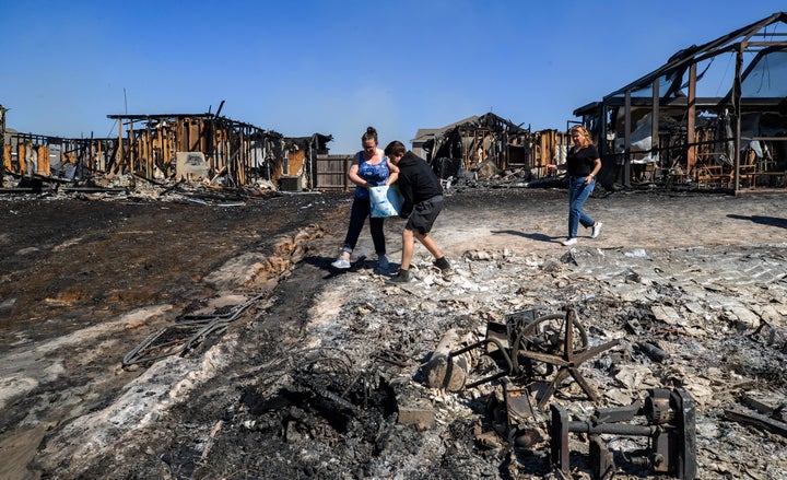 Emily Homeric, Robert O'Connor and Wandi Blanco pour water on hotspots behind homes in Panama City on Saturday.