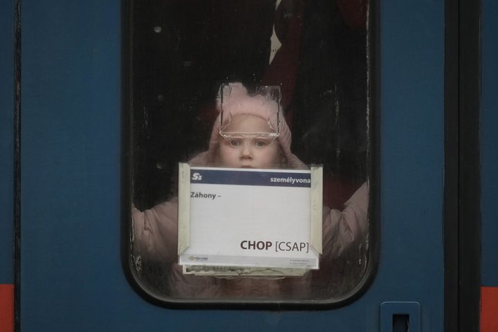 A young refugee girl fleeing Ukraine peers out the door window as she arrives at Zahony train station in Hungary. 