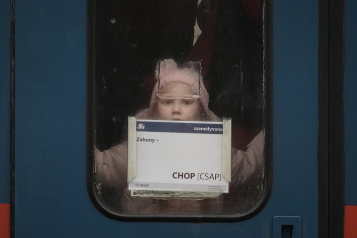 A young refugee girl fleeing Ukraine peers out the door window as she arrives at Zahony train station in Hungary. 