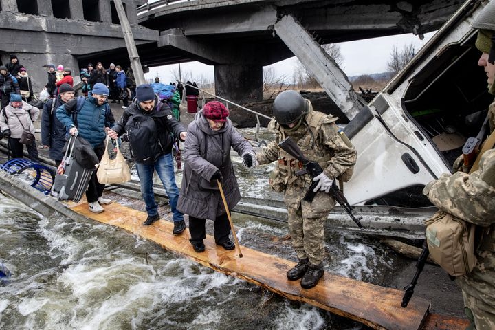 Residents of Irpin flee heavy fighting via a destroyed bridge as Russian forces entered the city.