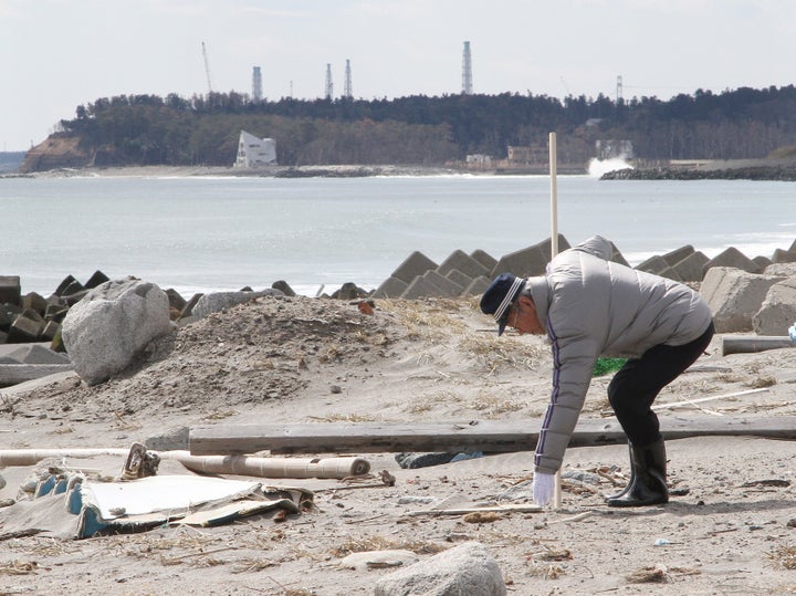 行方不明者の捜索をする男性。奥は東京電力福島第1原子力発電所(2013年、福島県浪江町)