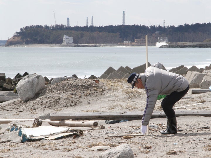 行方不明者の捜索をする男性。奥は東京電力福島第1原子力発電所（2013年、福島県浪江町）