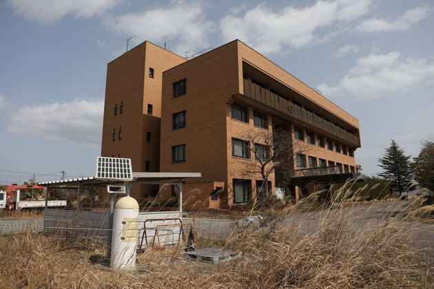 東京電力福島第１原発事故の影響で現在は使われていない双葉町役場。庁舎前には放射線測定用モニタリングポストが設置されている（2021年、福島県双葉町）