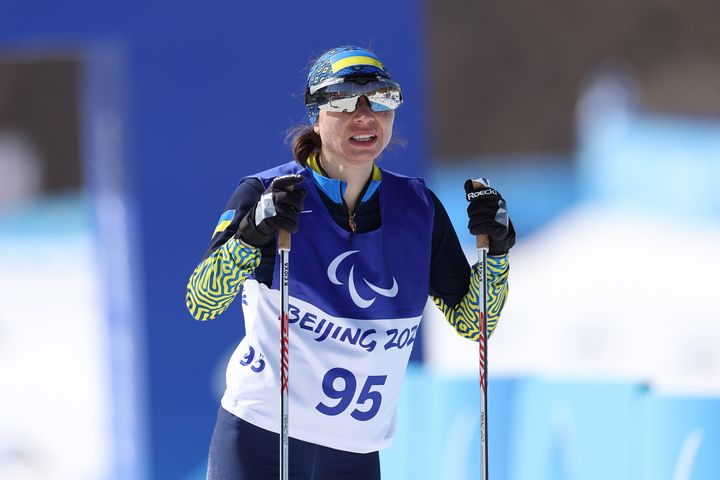 Oksana Shyshkova of Team Ukraine reacts after crossing the finish line in the Para cross-country skiing women's long-distance classical technique vision impaired event.