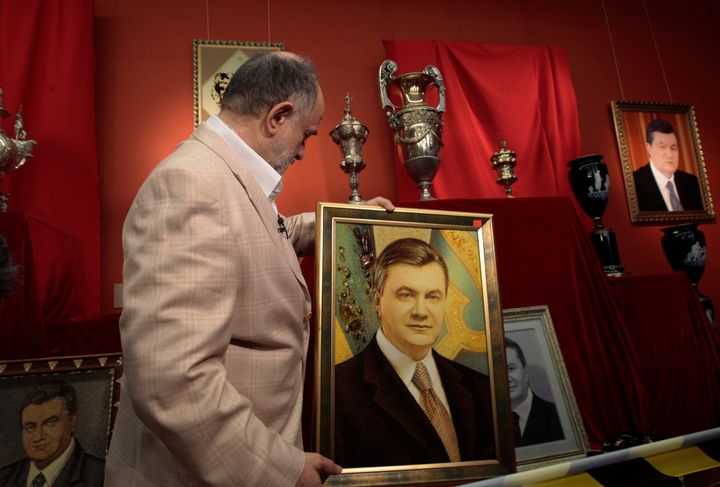 Υπάλληλος του Εθνικού Μουσείου Τέχνης στο Κίεβο, επιδεικνύει πορτρέτο του άλλοτε Ουκρανού Προέδρου Βίκτορ Γιανουκόβιτς, στη διάρκεια έκθεσης αντικειμενων με περιουσιακά του στοιχεία, στις 25 Απριλίου 2014. Η έκθεση είχε τον τίτλο "Mezhyhirya Code", παραπέμοντας στο όνομα του πάρκου όπου βρίσκεται η επιβλητική, τεράστια κατοικία όπου διέμενε ο Γιανουκόβιτς. (AP Photo/Sergei Chuzavkov)