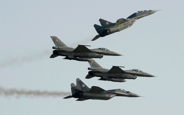 Polish Air Force MiG-29 fighter jets fly above and below two F-16 jets.