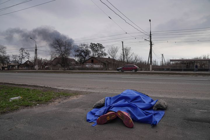 A deceased person lies covered in the street in Mariupol on March 7.