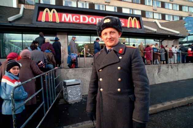 モスクワのゴーリキー通りに新しくオープンしたマクドナルドに入店しようとする人々の列のそばに立つソ連の警察官（1990年撮影）