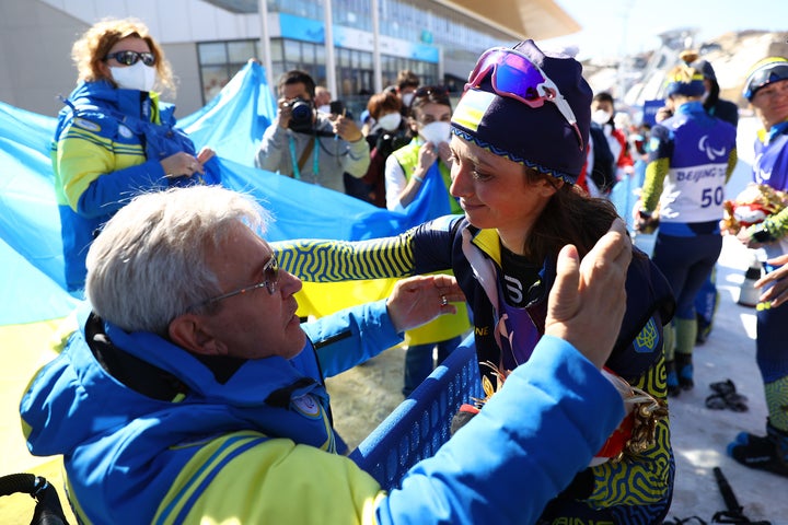 金メダルに輝いたバイアスロンのイリーナ・ブイ選手を祝福するスシュケビッチ会長（2022年3月8日）