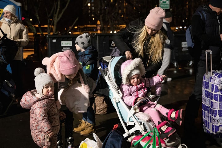 A mother and her children lining up in cold weather for buses departing to Netherlands in Warszawa Zachodnia station to other countries for resettlement. 