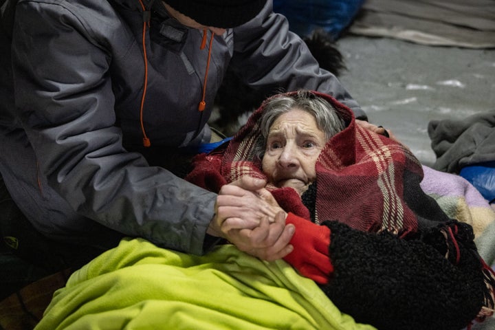 An elderly woman is assisted as Ukrainians cross an improvised path along a destroyed bridge to flee the city on March 8, 2022 on Irpin, Ukraine. Russia continues its assault on Ukraine's major cities, including the capital Kyiv, more than a week after launching a large-scale invasion of the country.