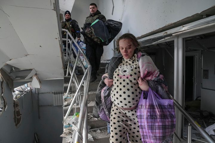 An injured pregnant woman walks downstairs in the damaged maternity hospital in Mariupol, Ukraine.