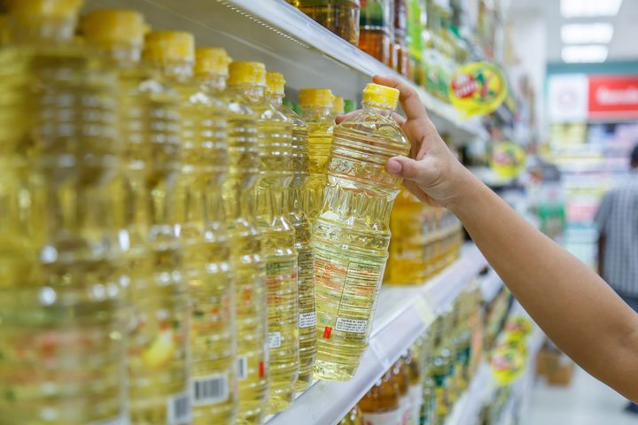 Una persona comprando aceite de girasol en un supermercado.