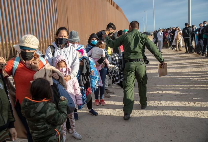 YUMA, ARIZONA - DECEMBER 07: Immigrant families are taken into custody by U.S. Border Patrol agents at the U.S.-Mexico border on December 07, 2021 in Yuma, Arizona. They had come through a nearby gap in the wall in previous days to seek political asylum in the United States. Border Patrol detention facilities in Yuma were overwhelmed in processing thousands of new arrivals, with many families trying to reach U.S. soil before the court-ordered re-implementation of the Trump-era Remain in Mexico policy. The policy requires asylum seekers to stay in Mexico for the duration of their U.S. immigration court process. (Photo by John Moore/Getty Images)