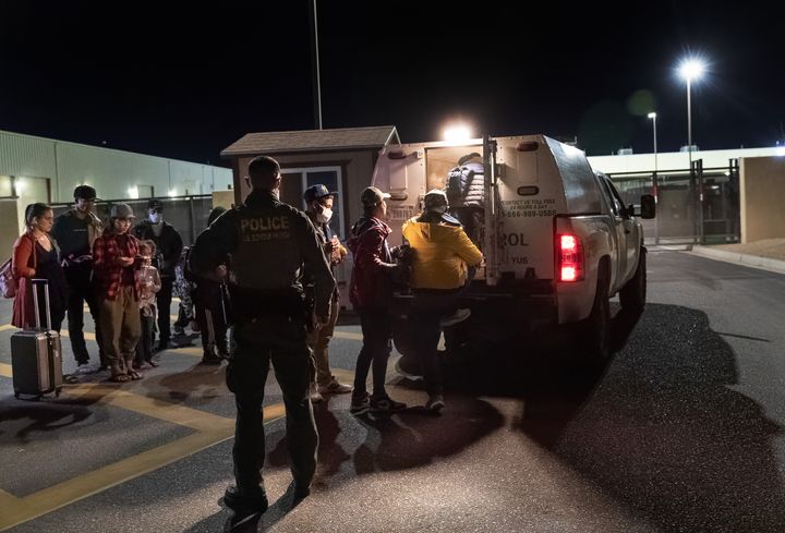 Immigrant families outside a U.S. Border Patrol detention facility are loaded into a vehicle to take them inside after walking from the U.S. Mexican border on December 08, 2021 through the city of Yuma, Arizona.