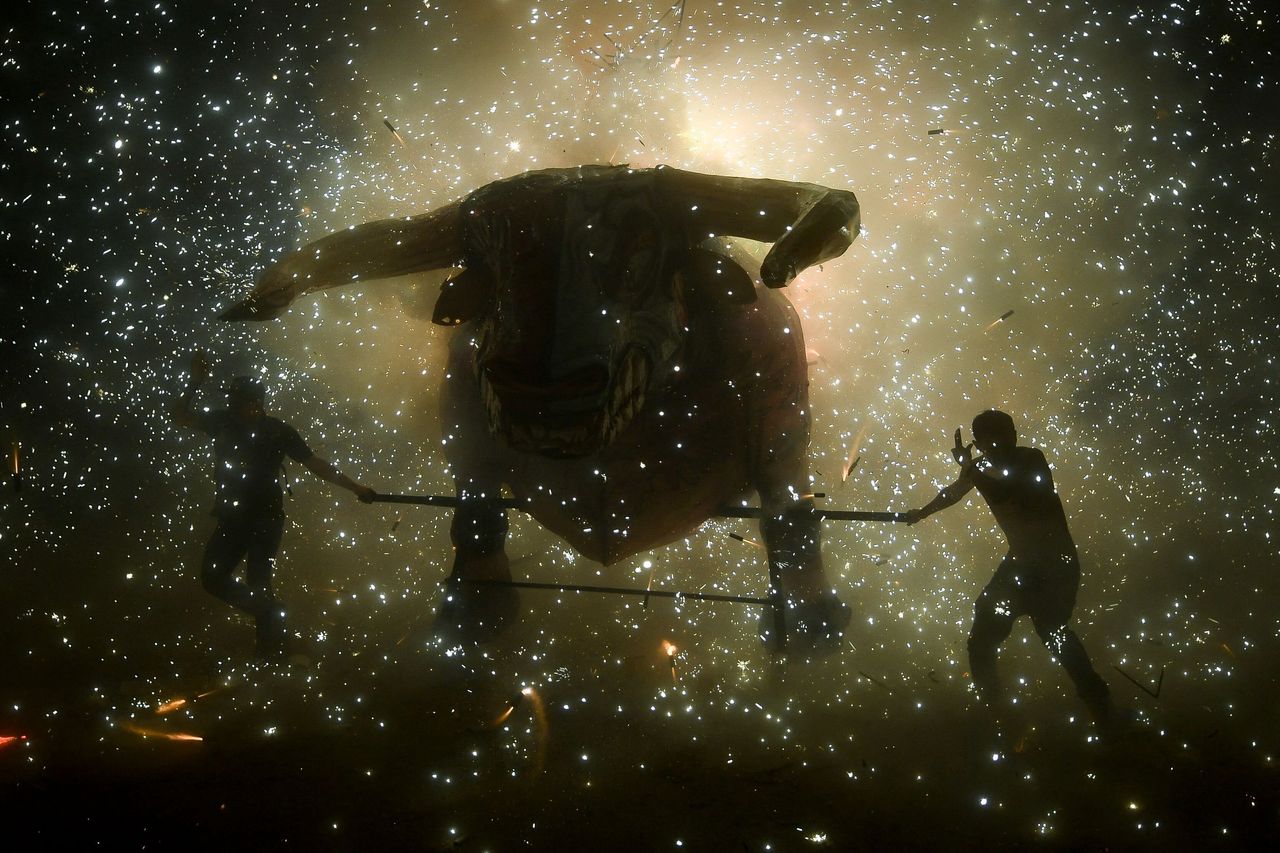 People shelter from fireworks before the traditional "torito" (little bull) made of paper, wood and fireworks during celebrations of San Juan de Dios in Tultepec on the outskirts of Mexico City on Tuesday. 