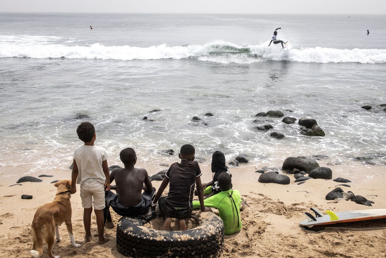 Young surfers look on as a competitor rides a wave during the Senegalese Surf Cup competition in Dakar on Sunday. In the last couple years surfing in Senegal has grown in size with some of Senegal's best surfers finding international recognition and sponsorship.