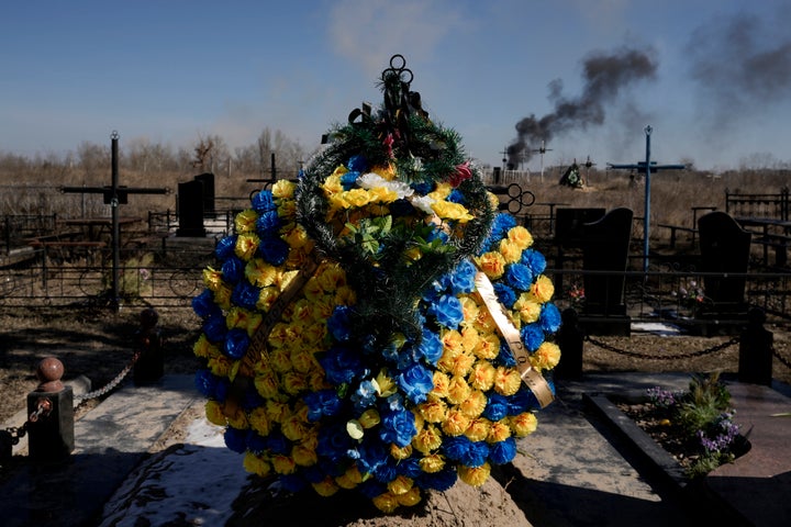 A smoke from shelling rises as a wreath of flowers is placed at a cemetery in Vasylkiv, southwest of the capital Kyiv.