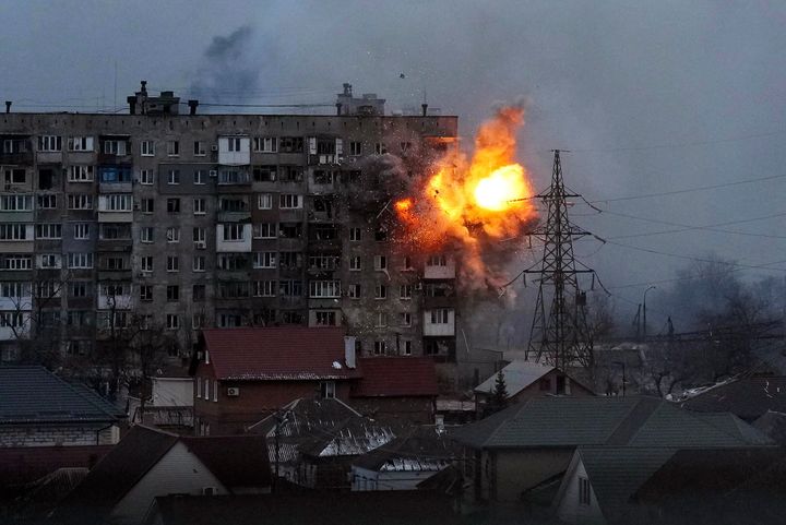 An explosion is seen in an apartment building after a Russian army tank fires in Mariupol.
