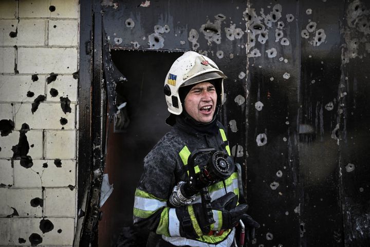 A firefighter gives instructions as he extinguishes a fire on a house after shelling in Kyiv.