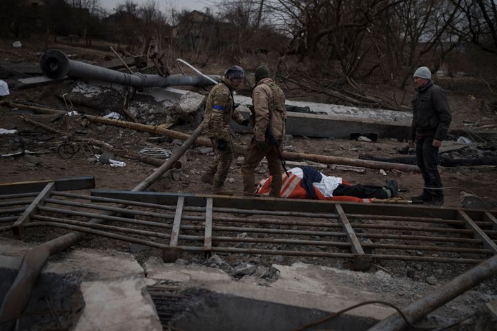 The body of a civilian, whose cause of death is unknown, lays on a stretcher on a path being used as an evacuation route out of Irpin, on the outskirts of Kyiv, Ukraine, Saturday, March 12, 2022. (AP Photo/Felipe Dana)