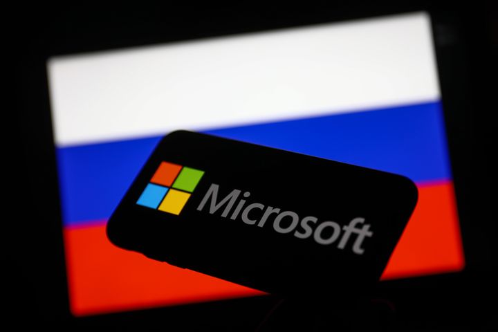 Microsoft logo displayed on a phone screen and Russian flag displayed on a screen in the background are seen in this illustration photo taken in Krakow, Poland on March 1, 2022. 