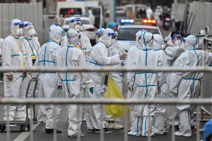 Officials and workers wearing protective gear are working as barriers are placed to close off streets around a locked down neighborhood in Shanghai on March 15, 2022.