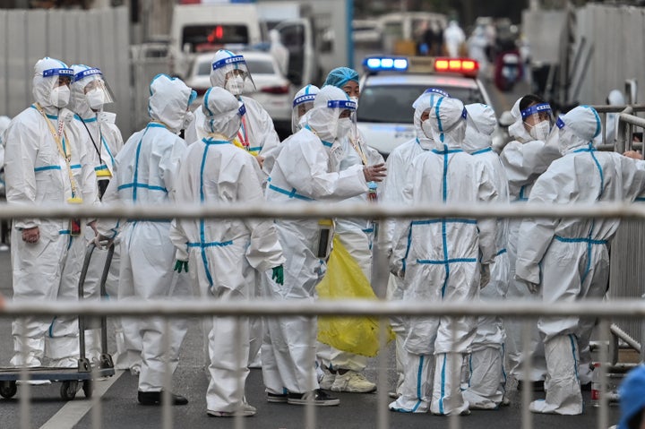 Officials and workers wearing protective gear are working as barriers are placed to close off streets around a locked down neighborhood in Shanghai on March 15, 2022. 