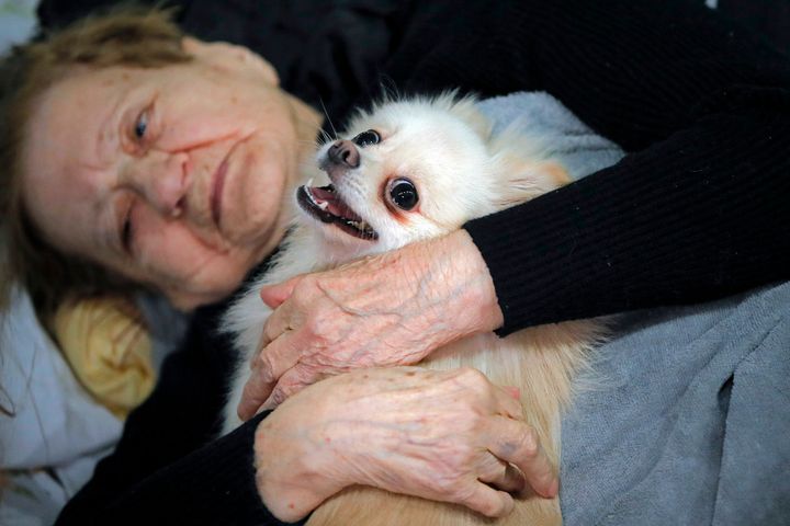 A refugee who fled the Russian invasion from neighboring Ukraine comforts her dog as they sit in a ballroom converted into a makeshift refugee shelter at a 4-star hotel & spa, in Suceava, Romania, Friday, March 4, 2022.