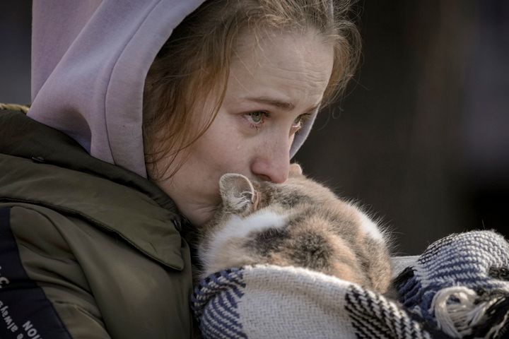A woman who was evacuated from Irpin cries kissing a cat wrapped in a blanket at a triage point in Kyiv, Ukraine, Friday, March 11, 2022. (AP Photo/Vadim Ghirda)