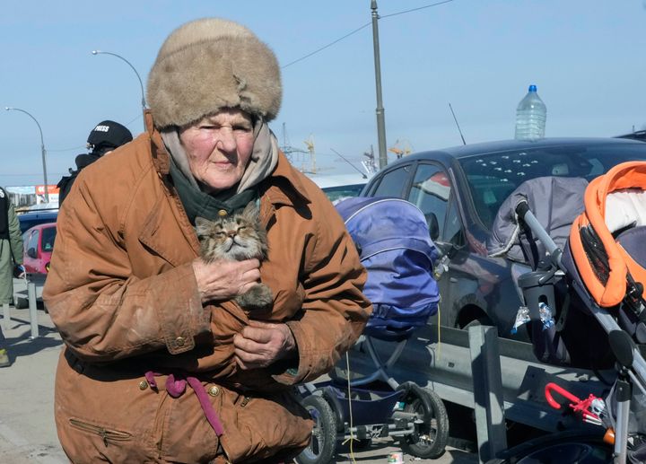 An elderly woman carries her cat as she flees from her hometown on the road towards Kyiv, in the town of Irpin, some 25 km (16 miles) northwest of Kyiv, Saturday, March 12, 2022. (AP Photo/Efrem Lukatsky)