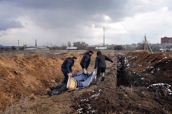 Dead bodies are put into a mass grave on the outskirts of Mariupol, Ukraine, Wednesday, March 9, 2022, as people cannot bury their loved ones because of the heavy shelling by Russian forces. 