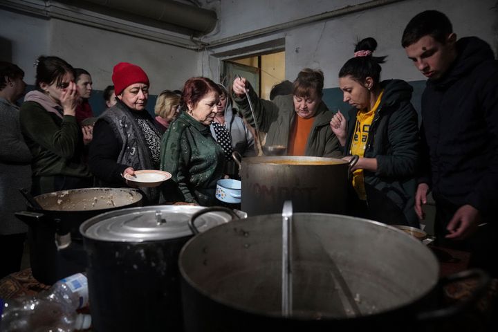 People queue to receive hot food in a improvised bomb shelter in Mariupol, Ukraine, on March 7, 2022. 