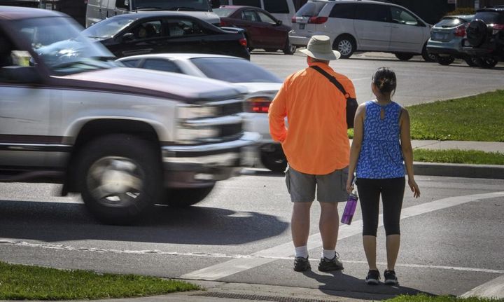 In this June 8, 2016, file photo, a maroon and silver truck drove, left, drives through the marked crosswalk in front of pedestrian volunteers Dave Passiuk and Nelsie Yang in St. Paul, Minn. 