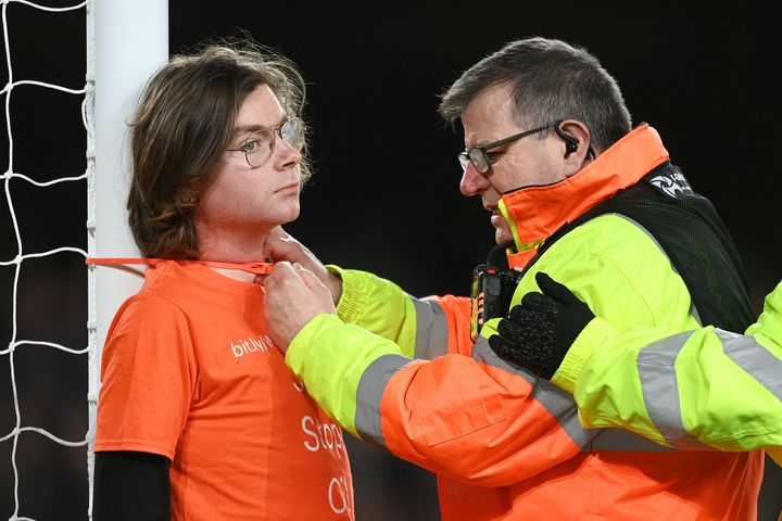 A steward attempts to cut cable ties after a fan ties himself to the net in protest during the Premier League match between Everton and Newcastle United at Goodison Park.