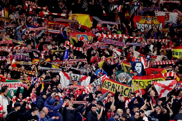 Aficionados del Atlético de Madrid muestran banderas durante un partido europeo contra el Manchester United en el estadio de Old Trafford.