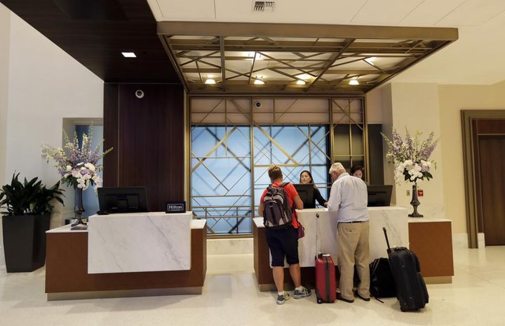 FILE- In this Sept. 5, 2018, file photo guests stand at the front desk at the Embassy Suites by Hilton hotel in Seattle's Pioneer Square neighborhood in Seattle.