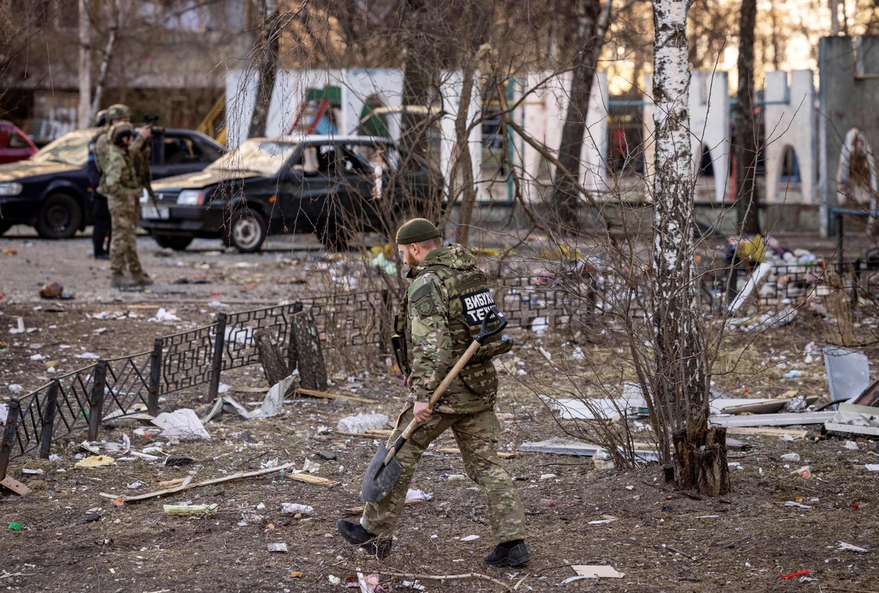 A member of the Ukrainian Territorial Defence Forces walks near a residential building which was hit by the debris from a downed rocket, in Kyiv, on March 20.