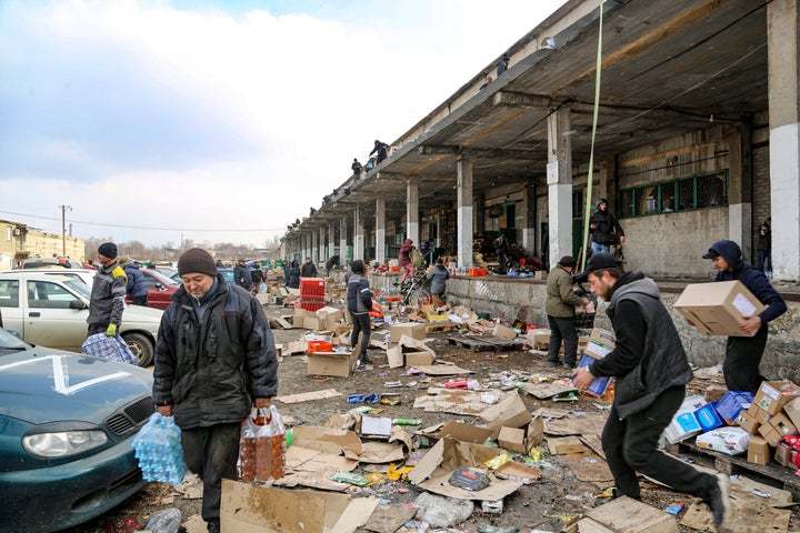 Residents carry water from a food warehouse on the outskirts of Mariupol, Ukraine. Supplies are reportedly running low.