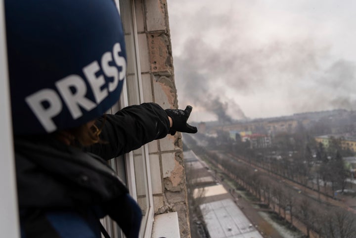 Associated Press photographer Evgeniy Maloletka points at the smoke rising after an airstrike on a maternity hospital, in Mariupol, Ukraine, on March 9, 2022.