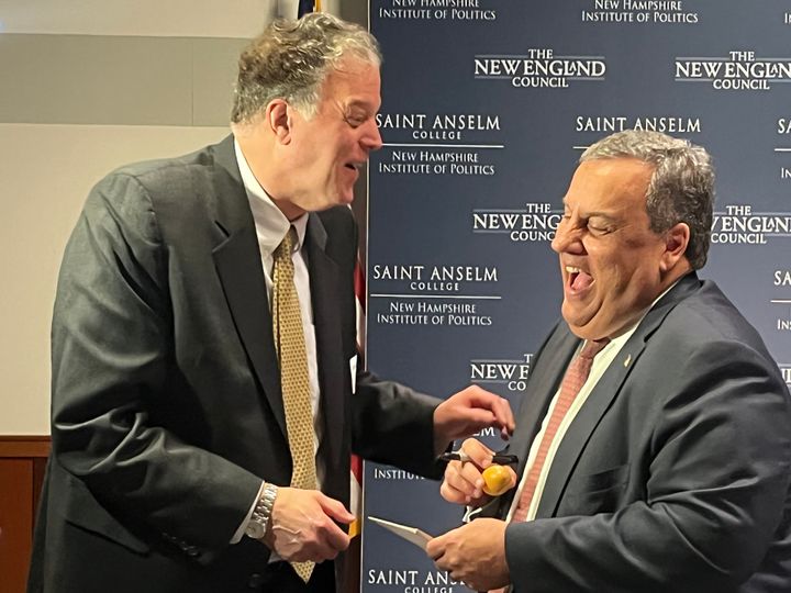 Former New Jersey Gov. Chris Christie (R), at right, signs wooden eggs for attendees at the "Politics and Eggs" breakfast at Saint Anselm College in Manchester, New Hampshire, a traditional stop for presidential hopefuls.