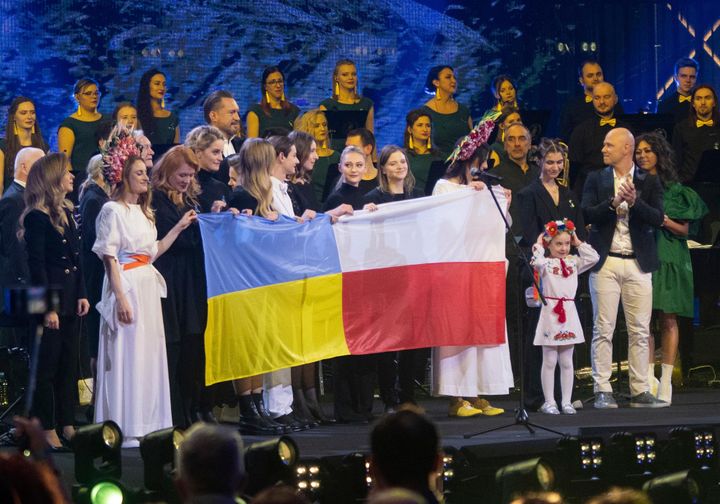 チャリティーコンサートでウクライナの国旗の横に立ち、髪飾りを抑えるアニソビッチさん（2022年3月20日）