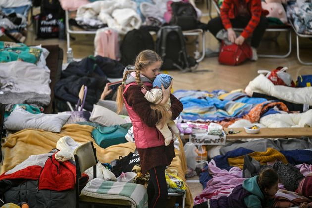 学校に設けられたウクライナ難民の避難所できょうだいを抱く少女＝2022年3月14日、ポーランド・プシェミシル