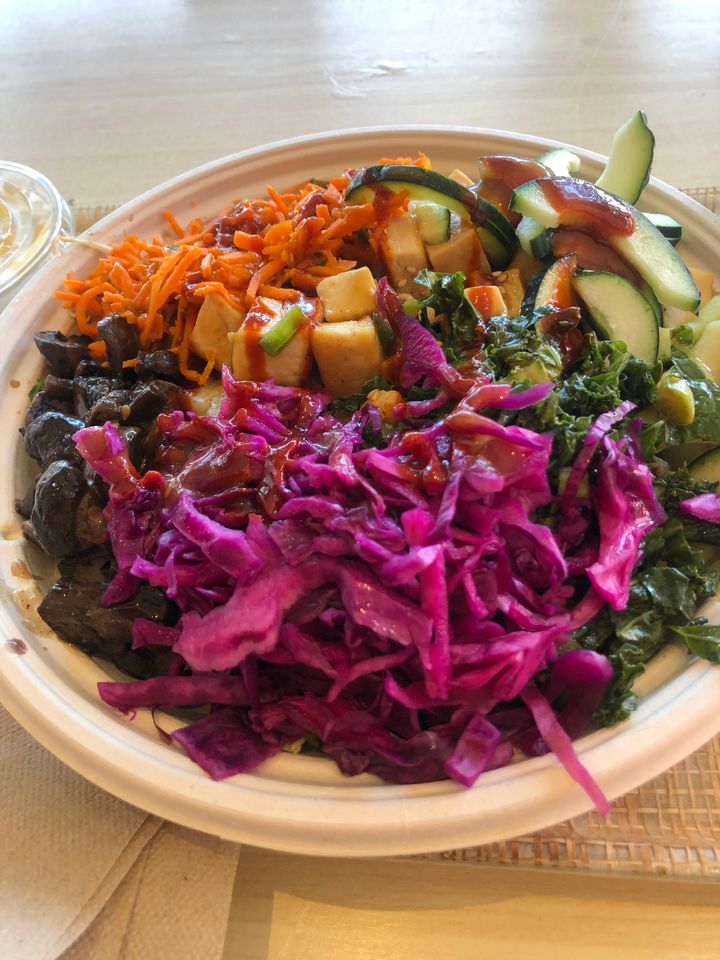 Bibimbap topped with tofu, mushrooms, carrots, cucumber, kale, purple cabbage and kimchi