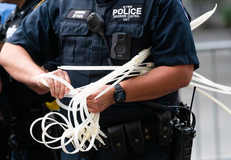 A New York Police Department officer gets zip ties ready handcuff protesters during a "Defund the Police" rally Sept. 13, 2021, at the Metropolitan Museum of Art during the MET Gala.