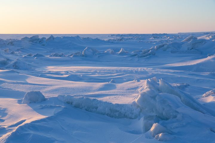 Winter Arctic landscape. The frozen sea. Ice hummocks near the sea coast. Ice covered with snow. Harsh cold polar climate.