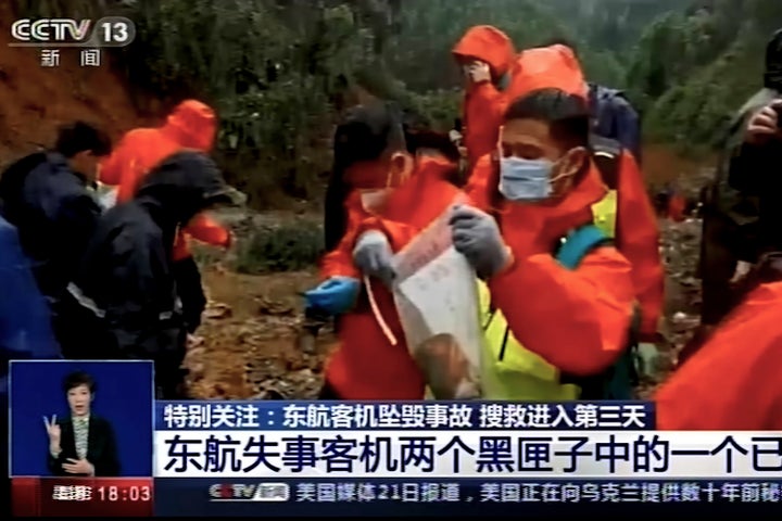 In this image taken from video footage run by China's CCTV, an emergency worker puts an orange-colored "black box" recorder into a plastic bag at the China Eastern flight crash site in Tengxian County in southern China's Guangxi Zhuang Autonomous Region on March 23, 2022.