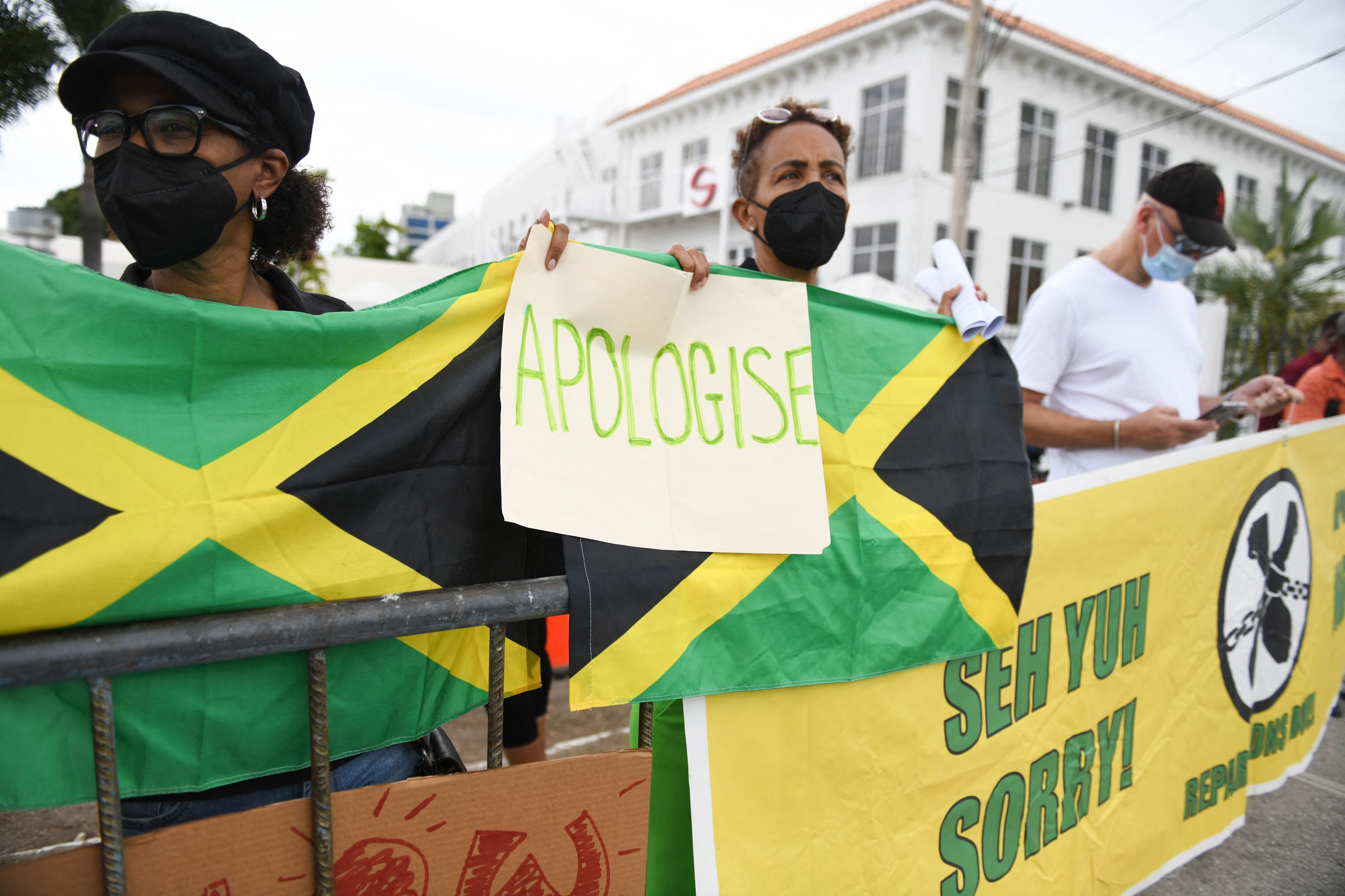 An "APOLOGISE" s visible all through the protest outside the entrance of the British High Commission.