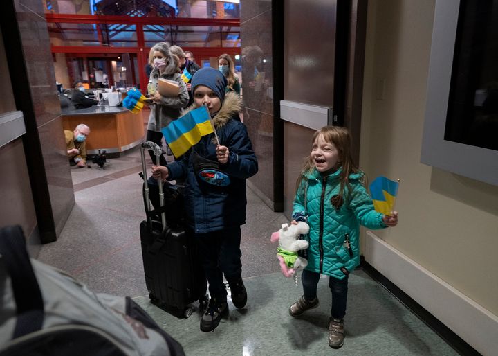 A young Ukrainian cancer patient smiles and waves a Ukrainian flag after arriving at St. Jude Children's Research Hospital in Memphis with her brother and mother.